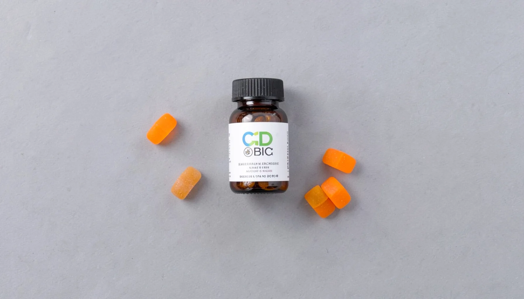 An overhead flat-lay of a small supplement jar with a few colorful gummies scattered on a soft grey surface, bathed in soft natural daylight